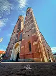 Low-angle view of the large Frauenkirche in Munich with two tall towers under a clear blue sky.