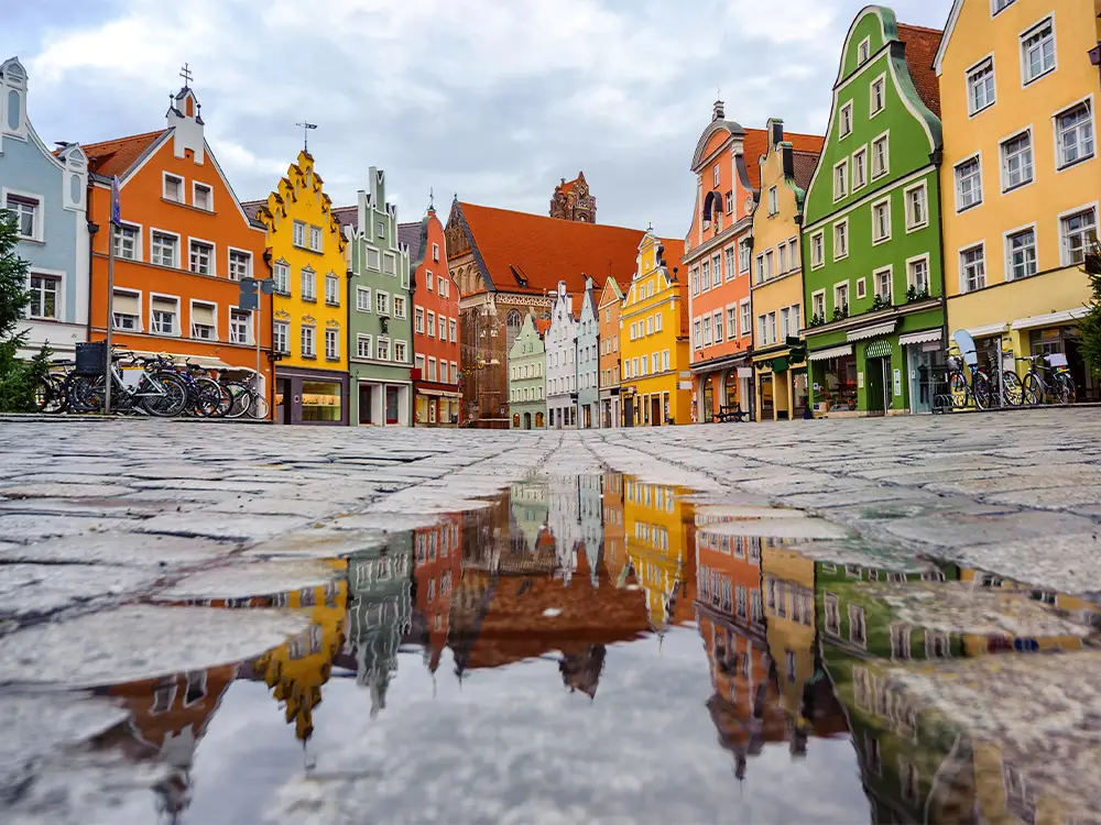 Reflections of colorful historic buildings in Landshut’s old town after a summer rain.