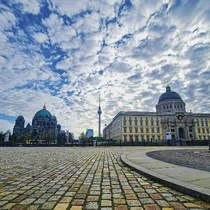 Wide-angle view of Berlin’s Museum Island with the Berlin Cathedral, Humboldt Forum, and TV Tower beneath a dramatic sky