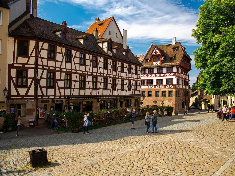 Half-timbered buildings and cobbled streets in Nuremberg’s Altstadt with people walking around.