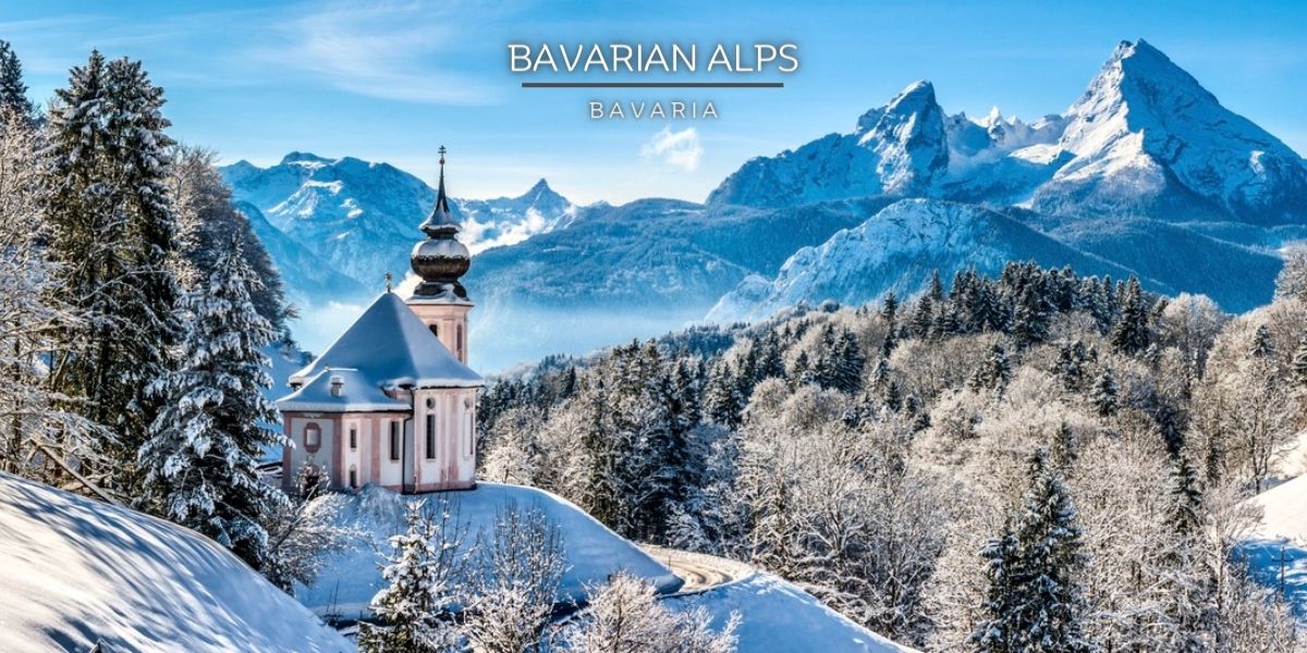 Church in the snow-covered Bavarian Alps Church on snow-covered mountain surrounded by trees and mountain range in the distance