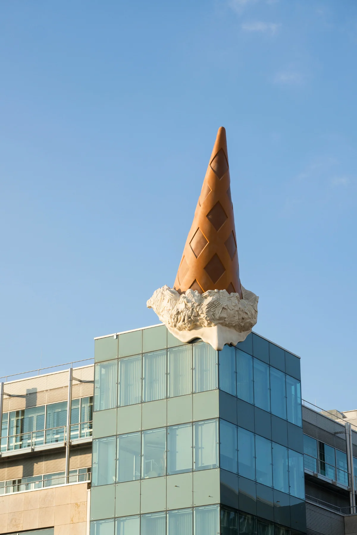 Art exhibit of an ice cream cone on top of glass panelled building in Cologne.