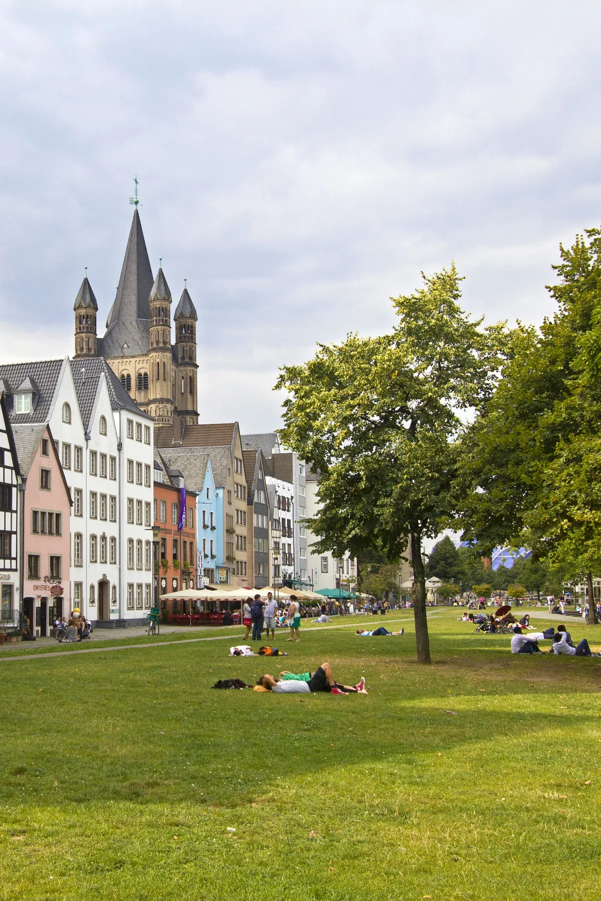 Old church tower and houses behind a park with people relaxing.