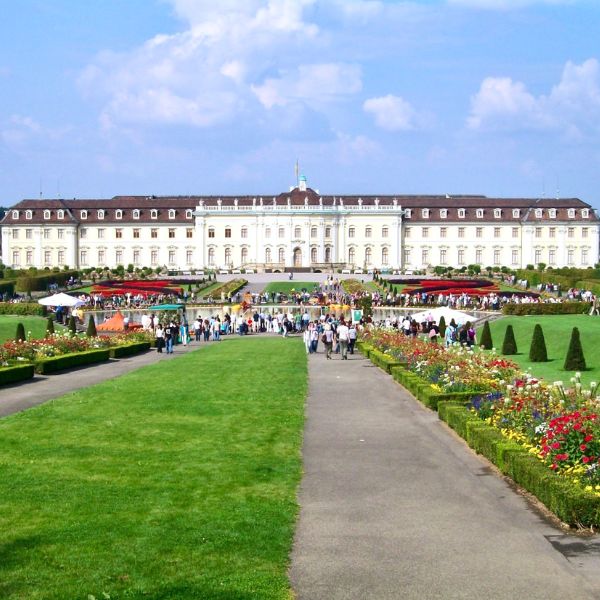 Crowds of people on the landscaped grounds of the white Ludwigsburg Palace in Stuttgart, Germany