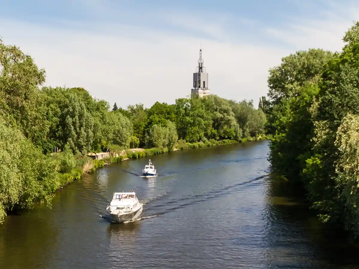 Cruising boats on Havel River in Potsdam, steam-pumping station tower beyond—relaxed Berlin day trip Brandenburg.