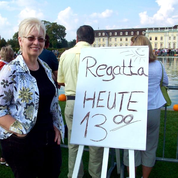 Oma Gerhild standing by sign for the Ludwigsburg Pumpkin Regatta, in front of the Ludwigsburg Palace