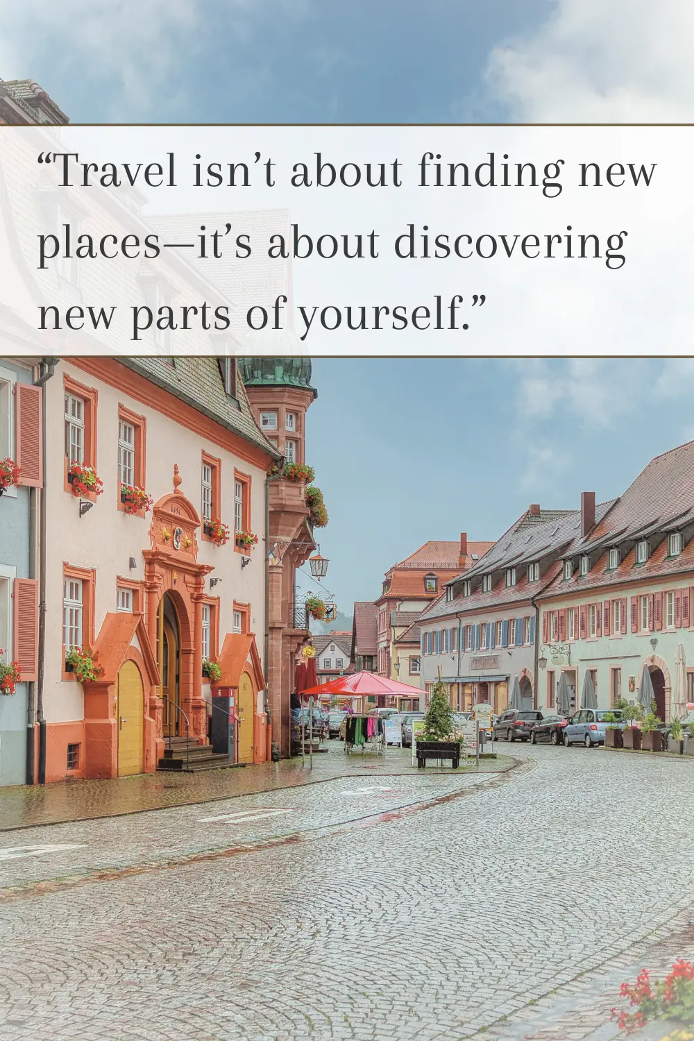 A wet cobblestone street lined with historic buildings, flower-adorned windows, and a small market.