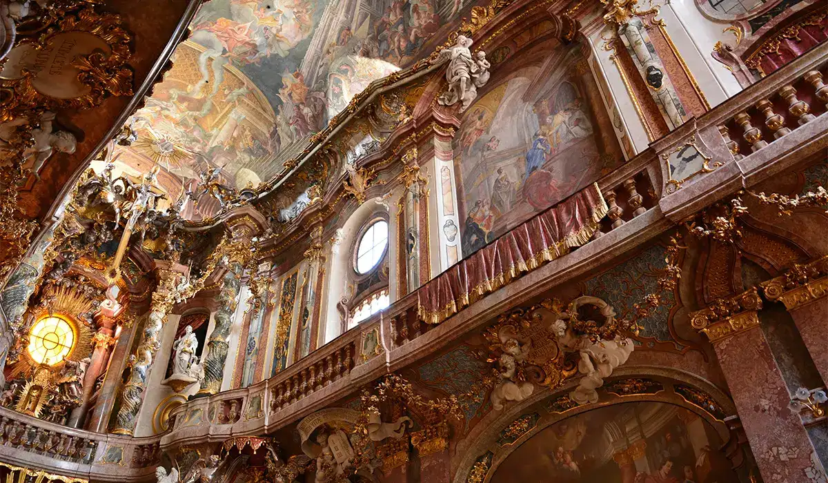 Lavish interior of Asam Church in Munich, featuring rococo-style decoration and gold accents.