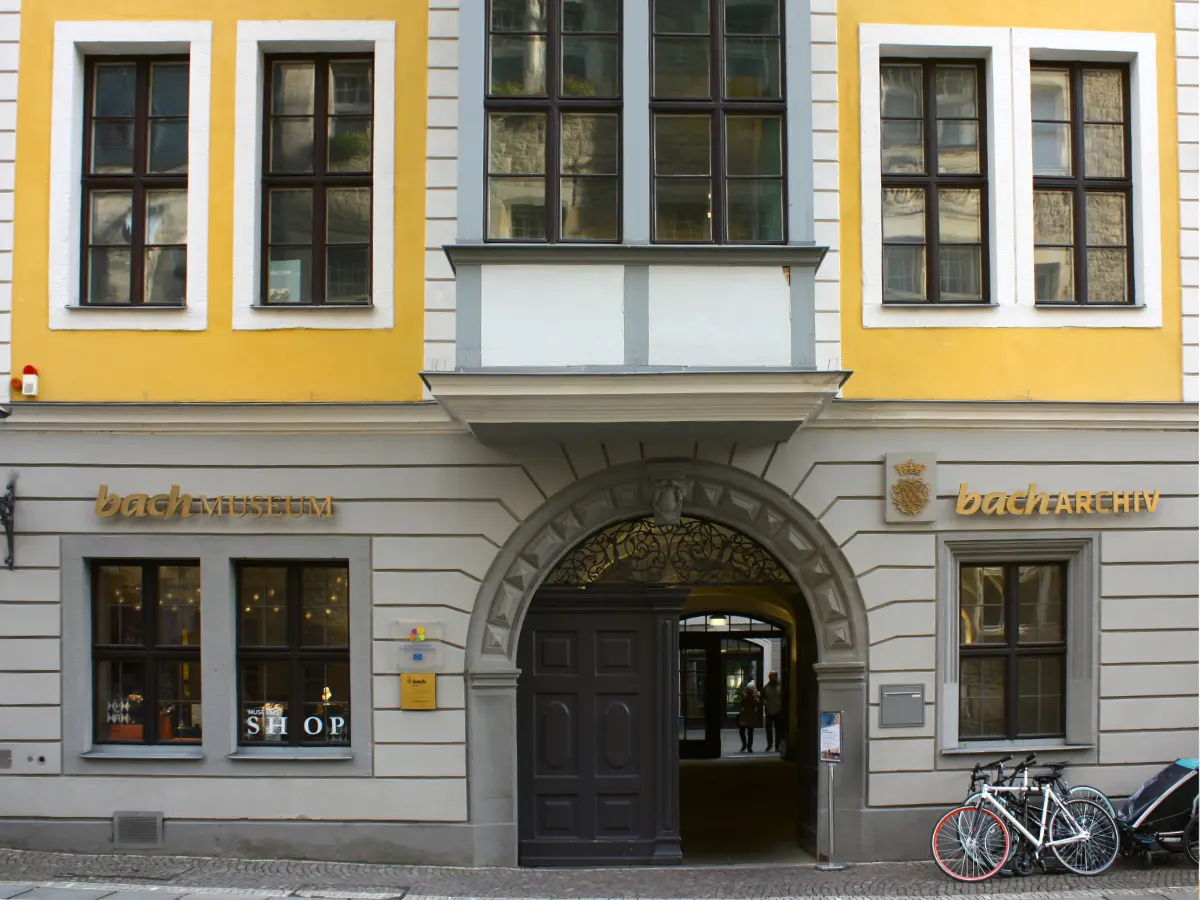 Bach Museum in Leipzig Facade of a historic building featuring the Bach Museum and Archive, with a large arched entrance, two bicycles parked outside, and several windows above.