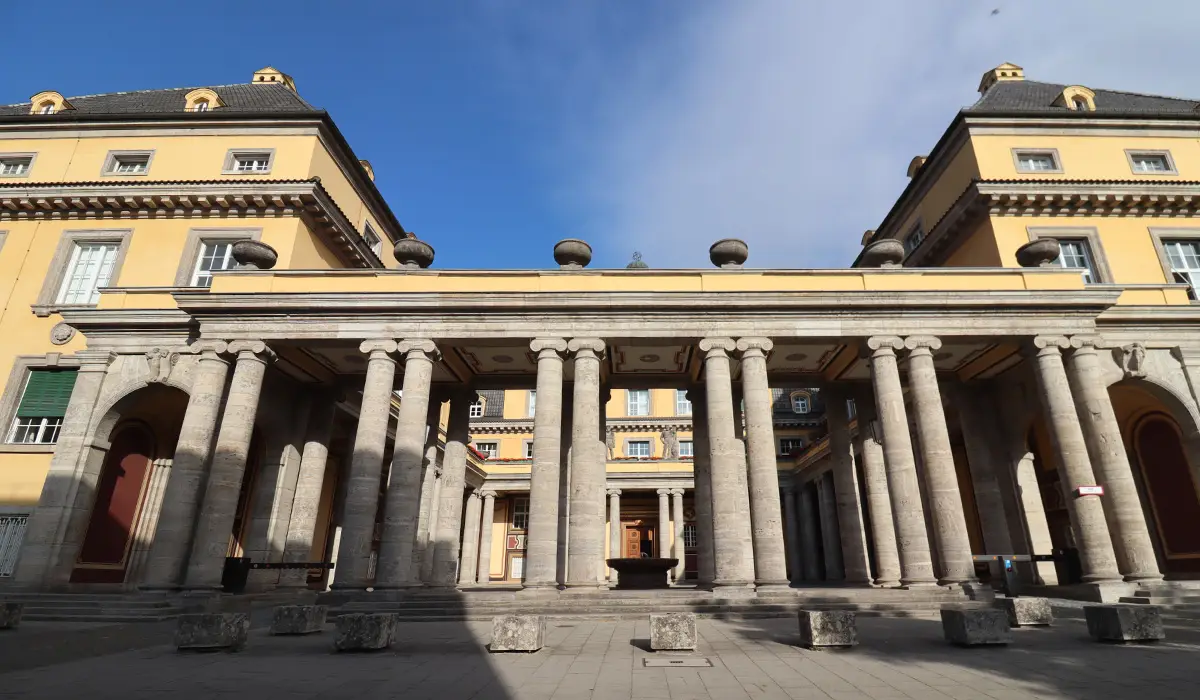 Large stone columns in front of the Bavarian State Opera in Munich on a sunny day.