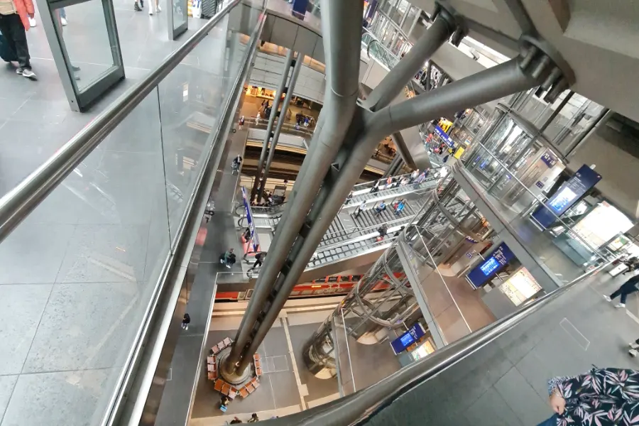 Multi-level glass interior of Berlin Hauptbahnhof with escalators and platforms on the floors below