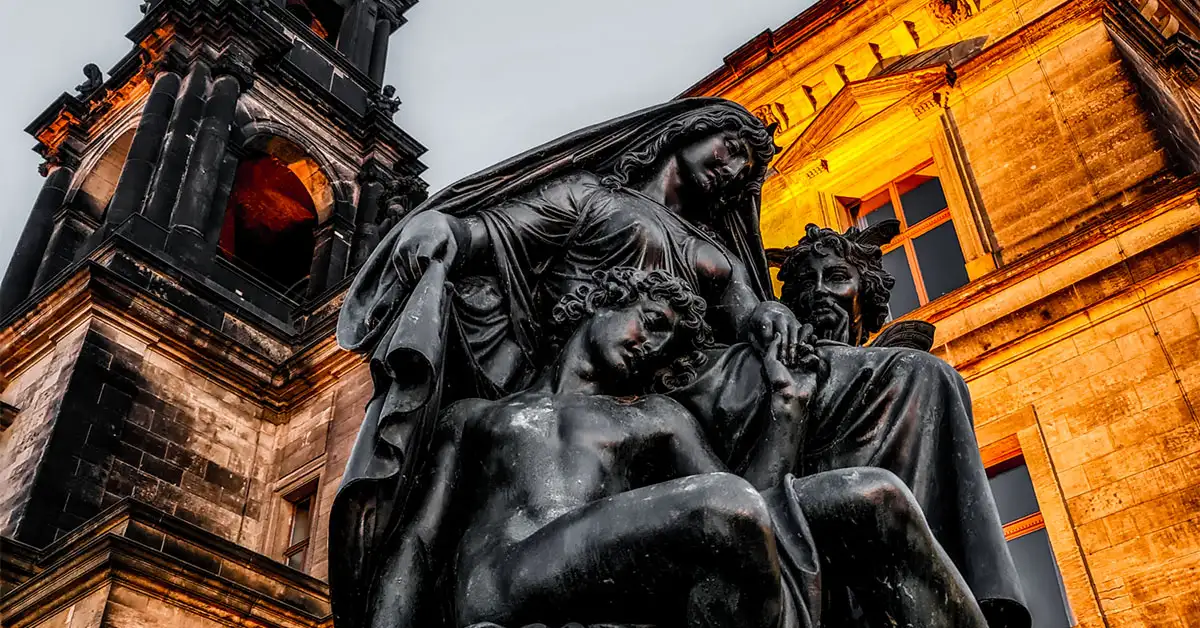 Dramatic view of a bronze statue on Brühl’s Terrace in Dresden, lit by golden-hour lighting against a historic building.