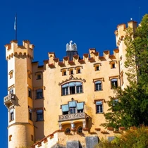 Close-up of Hohenschwangau Castle’s yellow facade and towers with a deep blue sky above