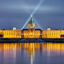 Charlottenburg Palace in Berlin illuminated at night with its grand baroque facade reflected in the water
