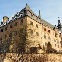 Rustic hilltop castle near Frankfurt with sloped roofs and turrets, partially dusted with snow