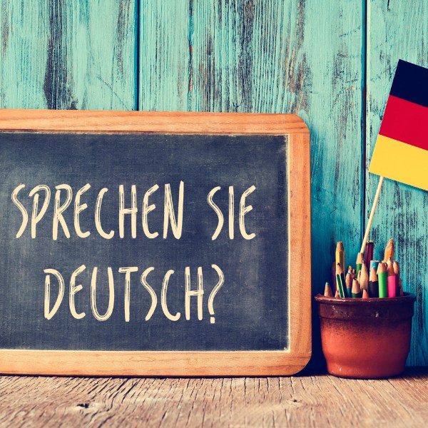 Do you speak German? Chalkboard with "Sprechen sie Deutsch?" written on it, pencils and German flag beside it.