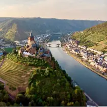 Aerial view of Cochem Castle perched above the Moselle River with vineyards and village below