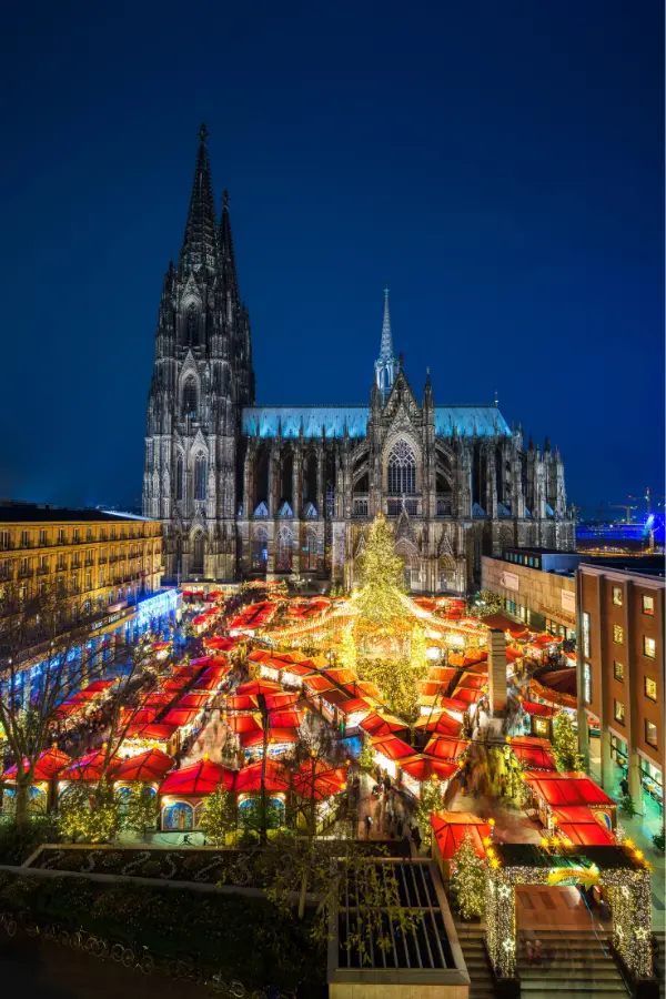 Cologne Christmas Market with a majestic Christmas tree and the towering Cologne Cathedral as the backdrop.