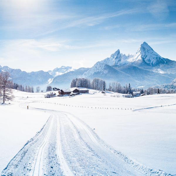 Cross-country ski track in Bavaria Snow-covered ground with ski chalet and mountains in the distance