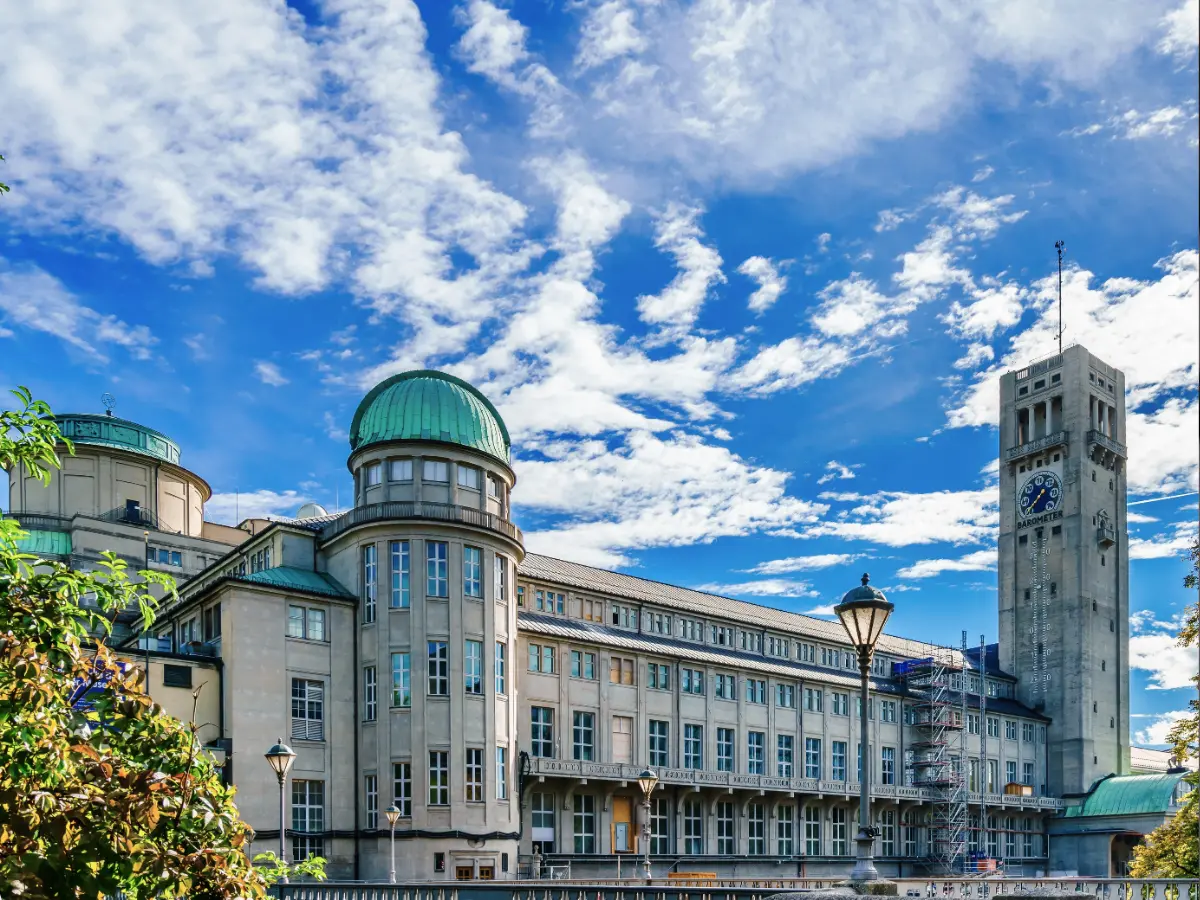 Deutsches Museum in Munich Deutsches Museum in Munich with green domes and a clock tower under a blue sky with scattered clouds.