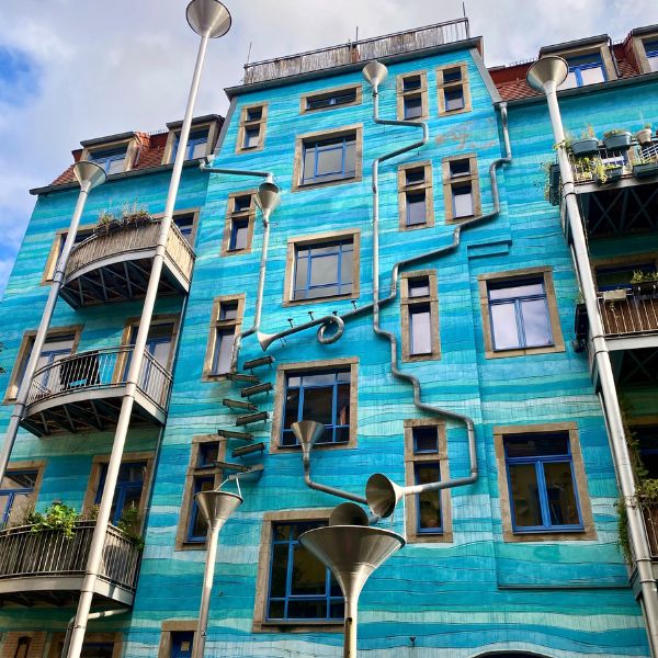 An artistic array of down pipes in front of a blue house at the Courtyard of Elements, Dresden