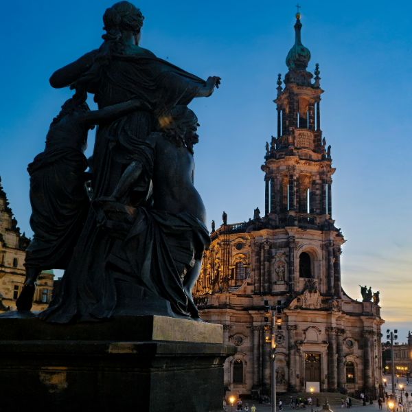 A statue facing the Dresden Cathedral lit up in the evening
