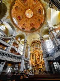 Interior of Dresden's Frauenkirche with intricate dome artwork, ornate organ, and large arched windows.