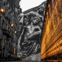 Twilight street view of Dresden's Fürstenzug mural with the Frauenkirche dome lit in the background, overlaid by a dramatic grayscale statue of mourning figures.