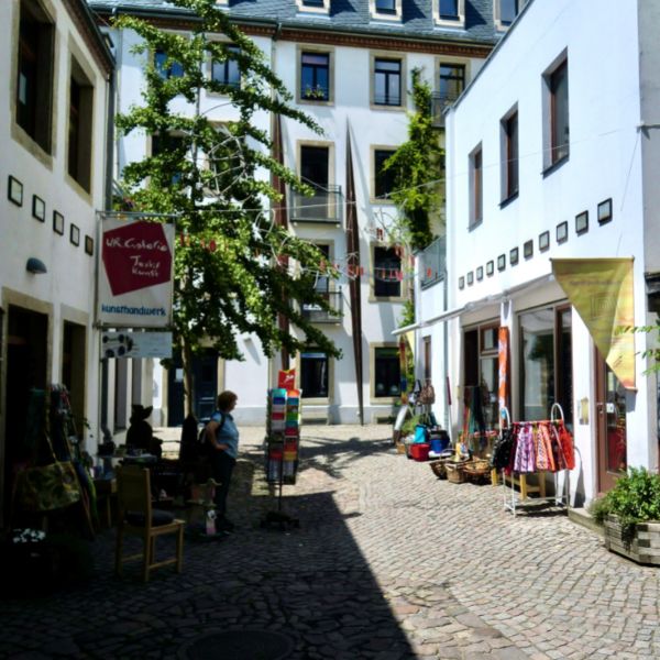 White buildings surround a courtyard with trees at the Hof der Metamorphosen, Dresden