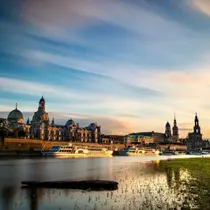Dresden skyline at golden hour with baroque buildings and Elbe River cruise boats in the foreground