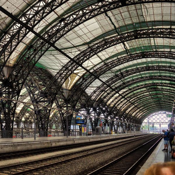 Steel grid framework of Dresden Train Station with rail lines and platforms.
