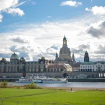 Skyline of Dresden’s Old Town along the Elbe River with church domes and baroque buildings under a partly cloudy sky