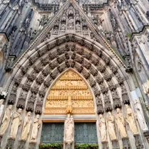 Gothic arched entrance of Cologne Cathedral adorned with statues and intricate sculptural details
