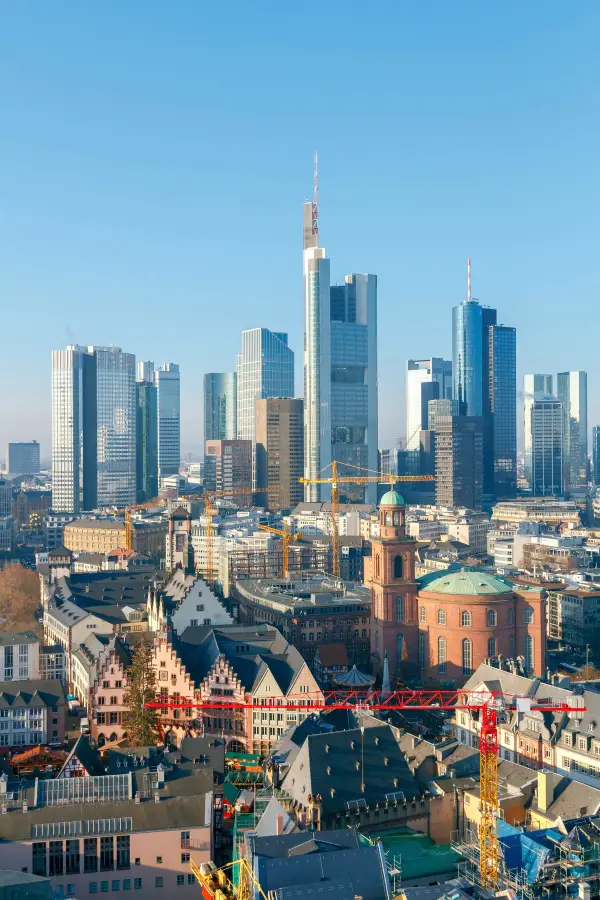Frankfurt city skyline with modern skyscrapers and historic buildings under a clear blue sky.