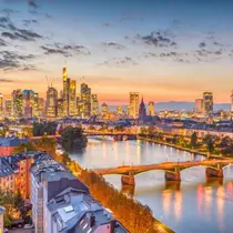 Skyline of Frankfurt at sunset with the Main River, bridges, and modern skyscrapers reflecting in the water