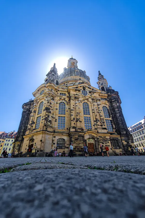 Low-angle view of a large, historic Frauenkirche in Dresden, Germany, with a domed roof surrounded by clear blue sky.
