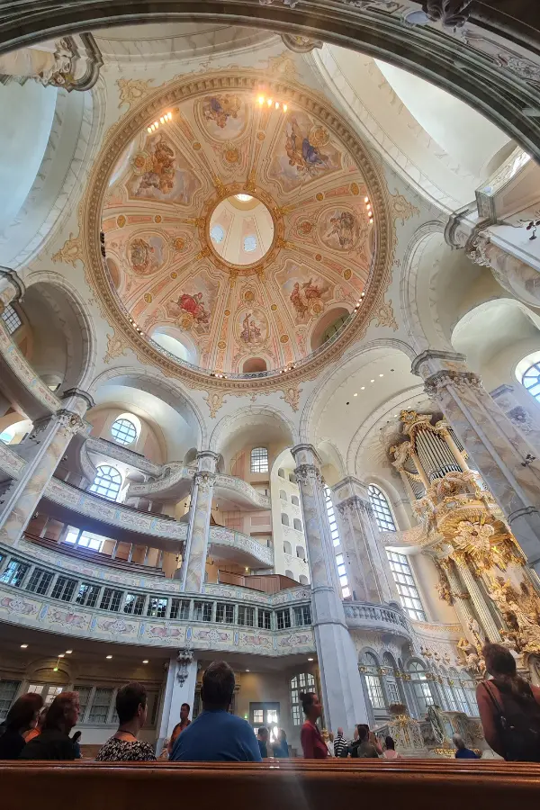 Interior view of Dresden's Frauenkirche, with a painted dome ceiling, ornate columns, and a large pipe organ.