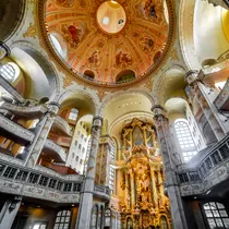 Interior of Dresden’s Frauenkirche featuring a richly decorated altar, soaring columns, and an ornate painted dome