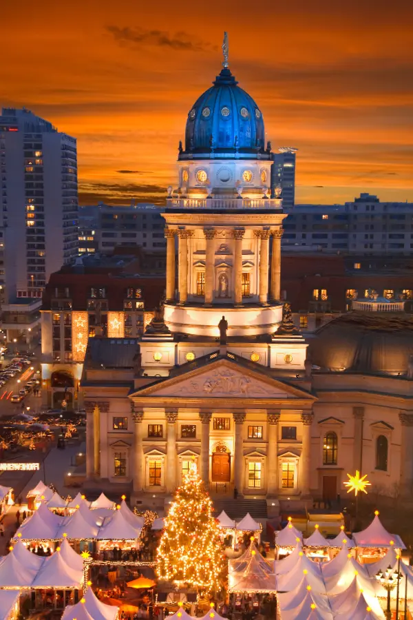 Berlin Gendarmenmarkt Christmas Market with glowing stalls and a view of the German and French Cathedrals.