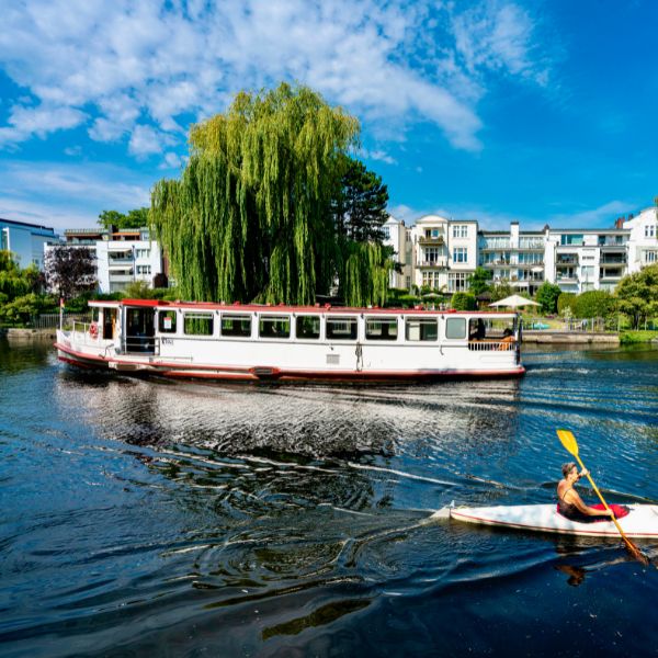 River cruise boat and kayaker paddling along river