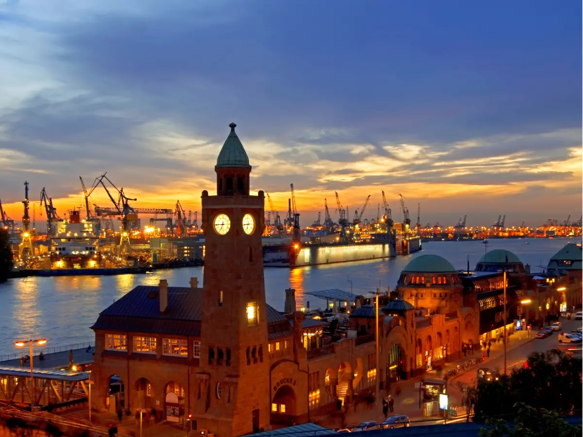 Lit up red buildings and boatyard in Hamburg at sunset.