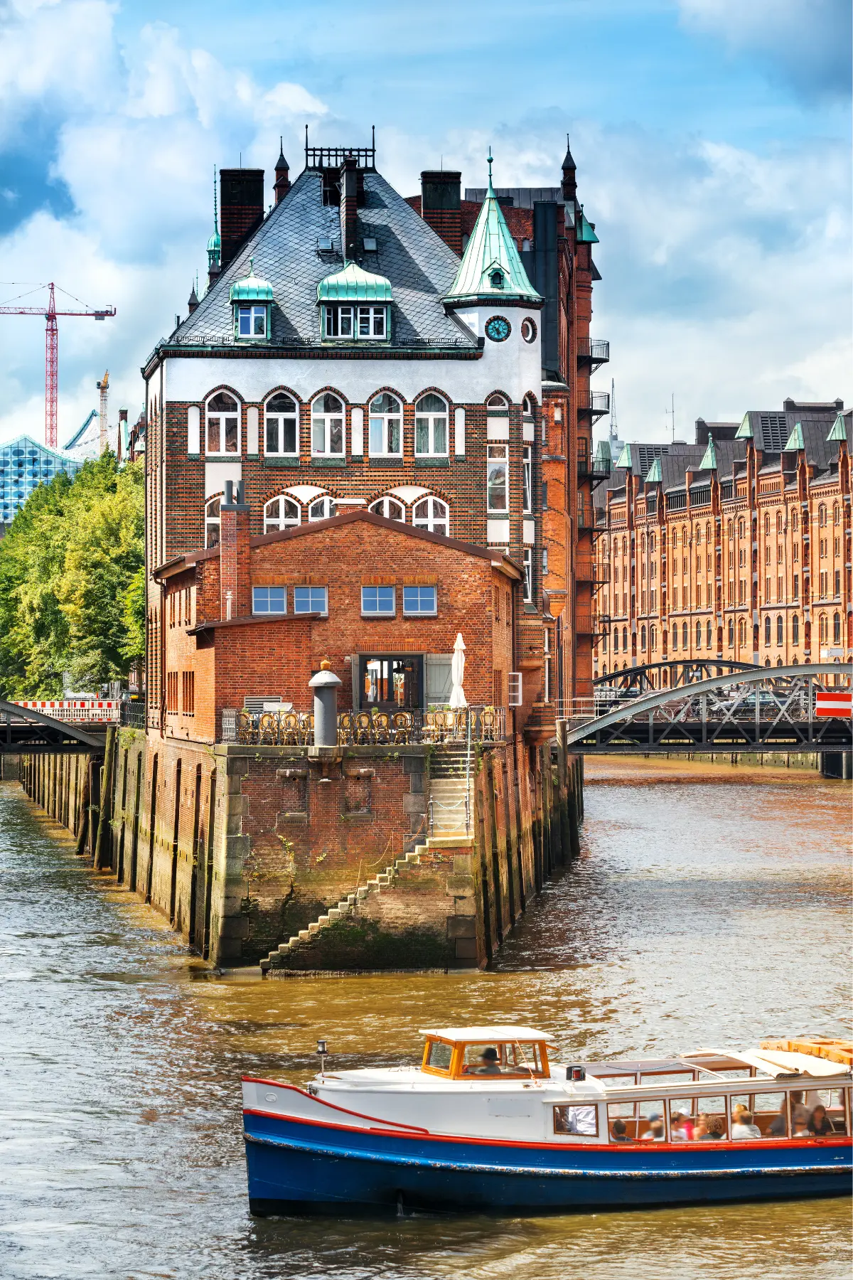 Red brick building along canal and boat in front under a partly cloudy sky