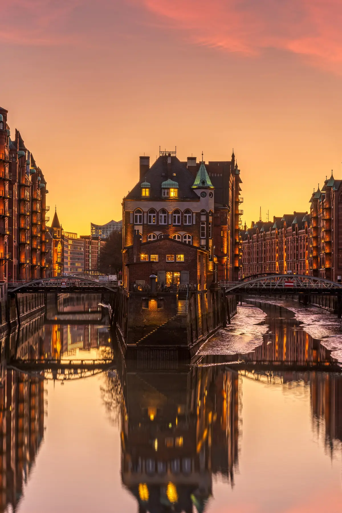 Red brick buildings line Hamburg canal at sunset.