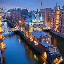 Evening view of Hamburg’s Speicherstadt district with illuminated warehouses and narrow canals