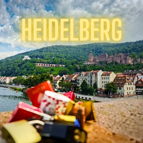 Heidelberg text and love locks in front of old buildings and castle on forested hill