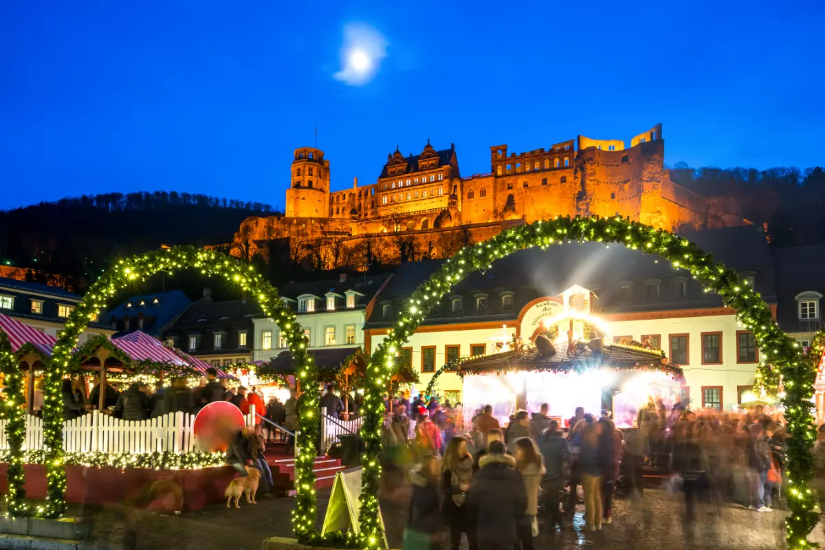 Heidelberg Christmas Market with festive lights and a view of Heidelberg Castle in the background.