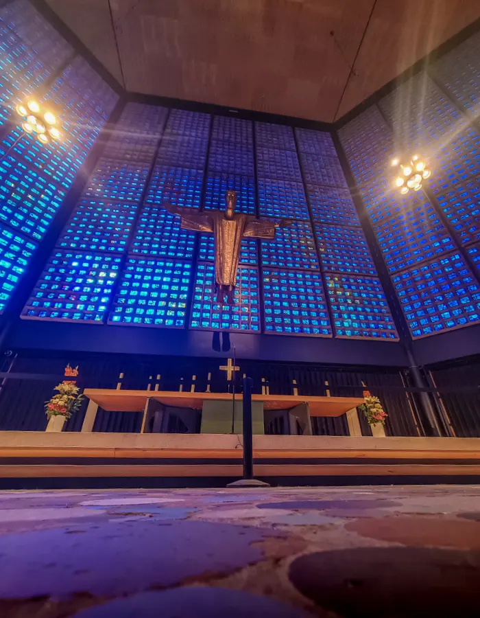 Blue glass walls and suspended bronze Christ inside the modern Kaiser Wilhelm Memorial Church in Berlin