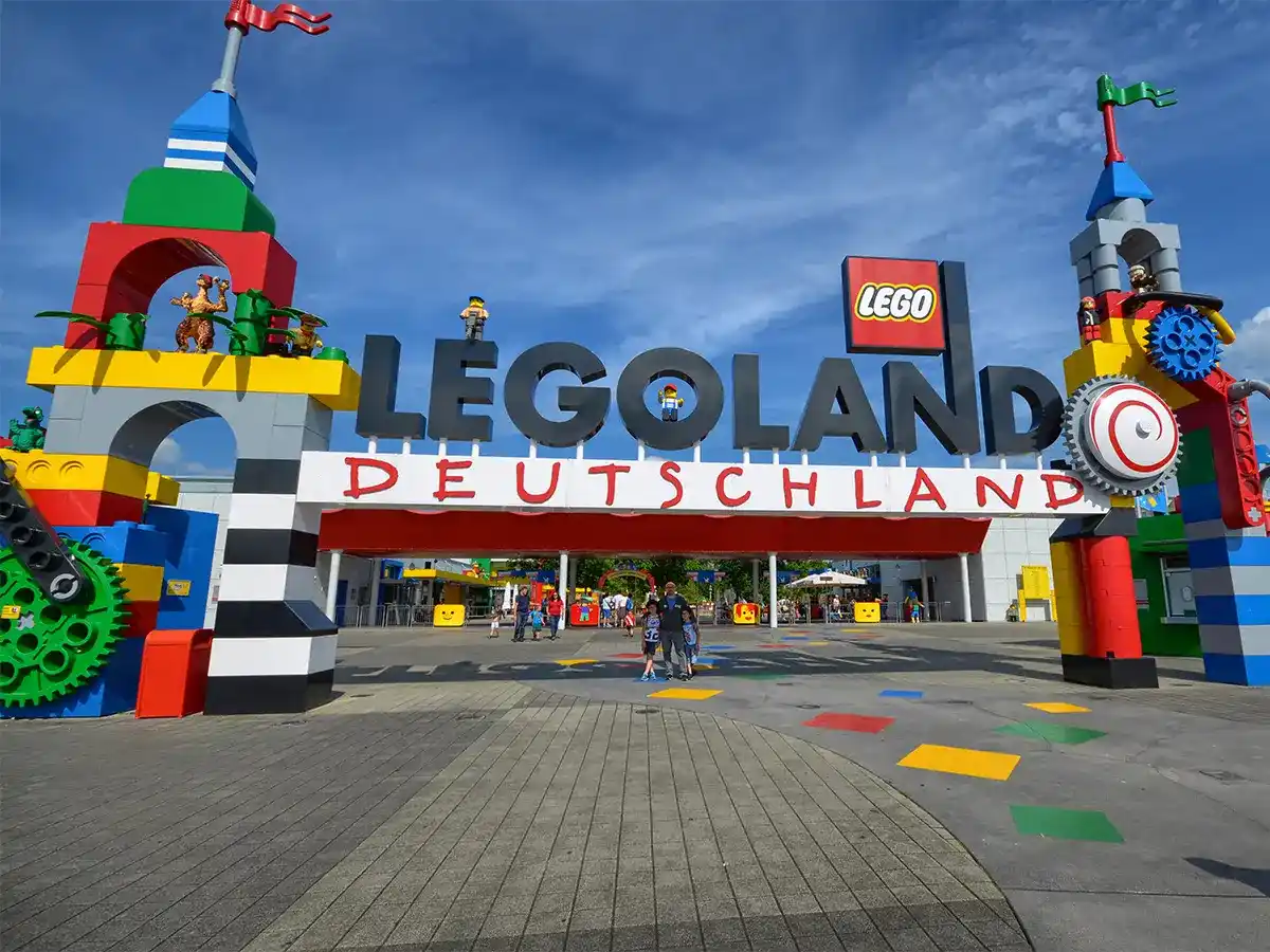 Entrance of LEGOLAND Deutschland with colorful LEGO brick structures and figures, under a clear blue sky.