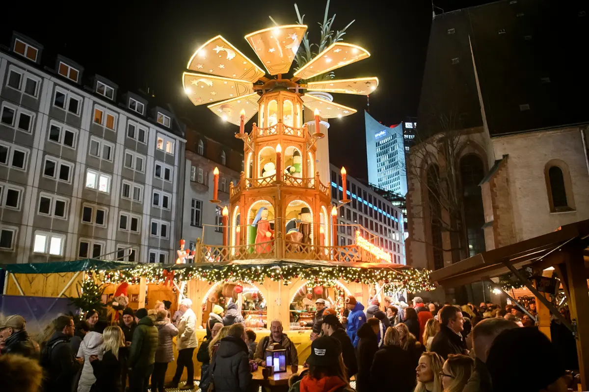Leipzig Christmas Market with large Christmas pyramid and the historic Old Town Hall illuminated for the holidays.