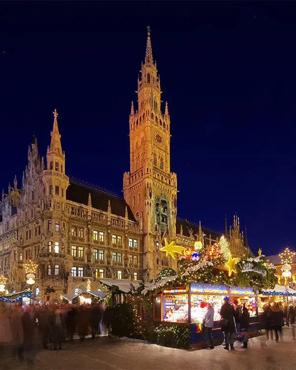 Christmas market stalls in front of the New Town Hall (Neues Rathaus) in Munich at night.